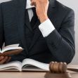 A lawyer in a suit reading a book at a desk with a gavel. A lawyer in a suit reading a book at a desk with a gavel.