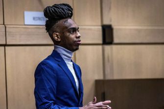 Rapper YNW Melly standing in a courtroom during his trial proceedings.