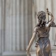 A bronze statue of Lady Justice holding scales, viewed from behind, set against a classical architectural backdrop. A bronze statue of Lady Justice holding scales, viewed from behind, set against a classical architectural backdrop.