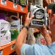 A person examining a bottle of Roundup weed killer in a store aisle among other cleaning products. A person examining a bottle of Roundup weed killer in a store aisle among other cleaning products.
