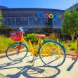 A colorful bicycle parked in front of the Google headquarters building, featuring the Google logo. A colorful bicycle parked in front of the Google headquarters building, featuring the Google logo.
