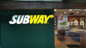 Subway restaurant exterior with logo and menu displayed.