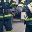 Firefighters adjusting their gloves while wearing protective gear, highlighting a lawsuit concerning toxic substances in firefighting equipment. Firefighters adjusting their gloves while wearing protective gear, highlighting a lawsuit concerning toxic substances in firefighting equipment.