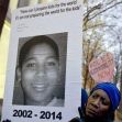 A person holding a sign with a photo of Tamir Rice and a quote about preparing children for the world, along with a smaller sign calling for police accountability. A person holding a sign with a photo of Tamir Rice and a quote about preparing children for the world, along with a smaller sign calling for police accountability.