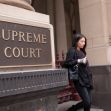A person walking past a sign for the Supreme Court building. A person walking past a sign for the Supreme Court building.