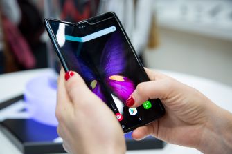 A person holding a Samsung smartphone with a close-up view of the display featuring a butterfly design.