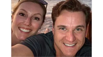 A smiling couple poses for a selfie at the beach.