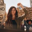 A group of women participating in a protest, holding signs and raising their fists in solidarity. A group of women participating in a protest, holding signs and raising their fists in solidarity.