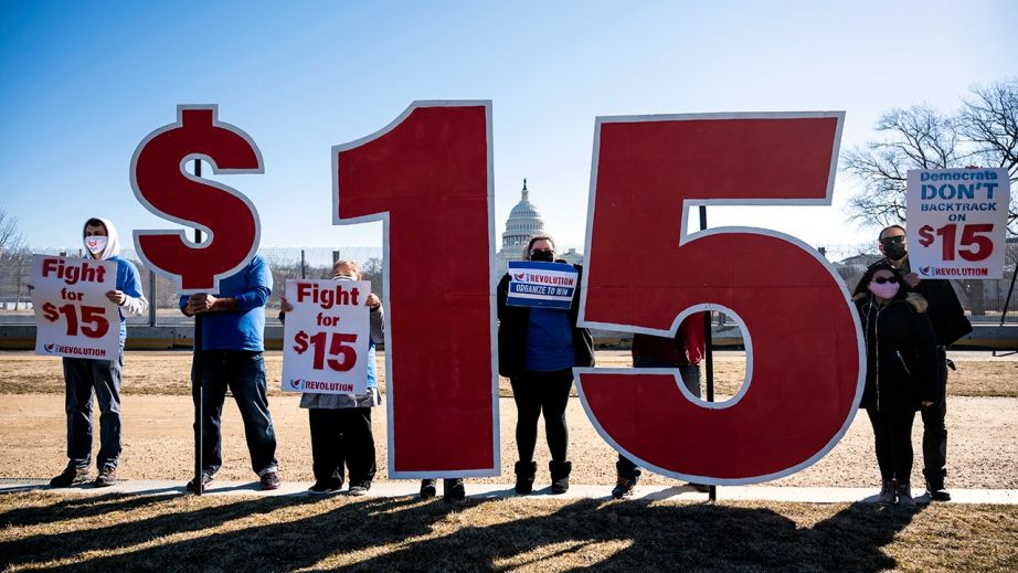Activists hold signs calling for Congress to includes a $15 federal minimum wage in a a COVID-19 relief bill outside the U.S. Capitol complex in Washington on Feb. 25, 2021.