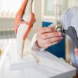 A medical professional demonstrating a hip implant attachment using a model of a knee joint. A medical professional demonstrating a hip implant attachment using a model of a knee joint.