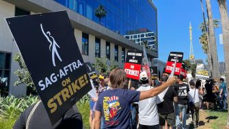 Protesters holding signs that read "SAG-AFTRA on STRIKE!" during a demonstration in support of the actors' union strike.