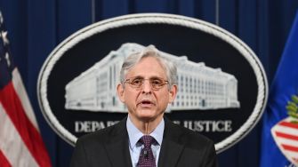 Merrick Garland, Attorney General of the United States, speaking at a press conference in front of the Department of Justice seal.