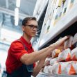 A warehouse employee in a red shirt organizing products on a shelf in a supermarket distribution center. A warehouse employee in a red shirt organizing products on a shelf in a supermarket distribution center.