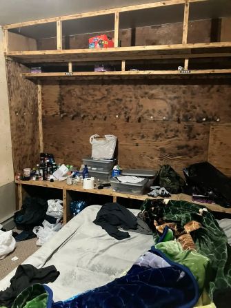 A cluttered and unsanitary living space with a makeshift bed, disorganized personal items, and overall poor conditions at a dairy farm.