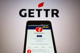 Logo of GETTR with a smartphone displaying the support account on the platform.