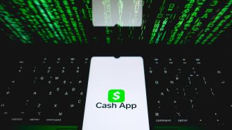 Cash App logo displayed on a smartphone with a backdrop of green digital code.