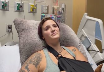In a hospital bed, a protester with an arm sling and visible tattoos appears to be recovering from injuries sustained during a Black Lives Matter demonstration.