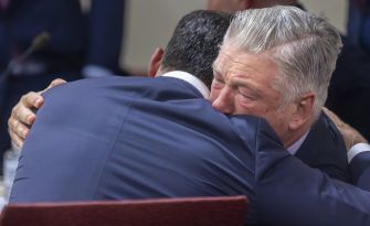 Alec Baldwin and a supporter embrace in a courtroom following the dismissal of involuntary manslaughter charges against him.