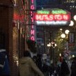 Neon sign for Union Gospel Mission in Seattle, with individuals walking past in the evening. Neon sign for Union Gospel Mission in Seattle, with individuals walking past in the evening.