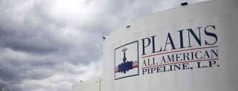 Logo and storage tanks of Plains All American Pipeline against a cloudy sky.