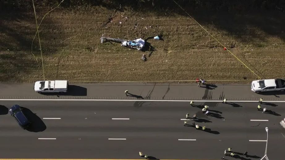 In this image taken with a drone, emergency personnel work at the scene of a helicopter crash on the side of Interstate 77 South in Charlotte, N.C., Tuesday, Nov. 22, 2022. The family of a meteorologist who was killed last year in a helicopter crash in North Carolina is suing a maintenance facility and the company that owned and operated the aircraft.(Alex Slitz/The Charlotte Observer via AP, File via Live 5 WCSC)