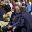 A group of people seated outdoors, engaged in conversation, with some wearing masks. A group of people seated outdoors, engaged in conversation, with some wearing masks.
