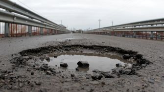 An image of a large pothole filled with water on a road, highlighting a potential tripping hazard.
