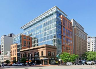 An urban building with a modern glass facade in a commercial area, featuring a blend of contemporary and historical architecture.