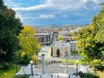 A scenic view of a university campus with greenery and buildings under a bright sky.