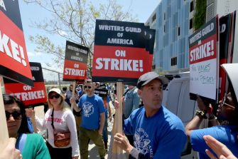 Striking workers holding signs that read "Writers Guild of America ON STRIKE!" during a labor protest.
