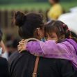 A woman holds a child in an outdoor setting, with others in the background, highlighting the emotional impact of immigration policies. A woman holds a child in an outdoor setting, with others in the background, highlighting the emotional impact of immigration policies.