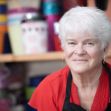 A florist posing in her shop, surrounded by colorful flower containers. A florist posing in her shop, surrounded by colorful flower containers.