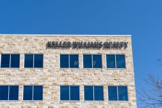 Signage of the Keller Williams Realty office building against a clear blue sky.