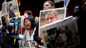Families of Boeing crash victims hold photos and signs during a protest, urging the Department of Justice to impose a significant fine on the company.