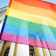 A rainbow pride flag waving in front of a historic building. A rainbow pride flag waving in front of a historic building.