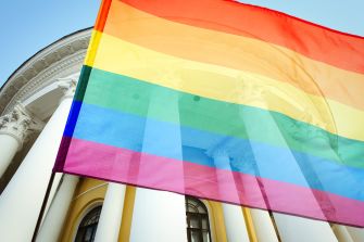 A rainbow pride flag waving in front of a historic building.