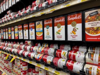 Canned soup displayed in gravity-fed racks at a grocery store.