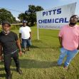 Three Black men stand in front of a sign for Pitts Chemical, highlighting their involvement in a lawsuit against Pitts Farm Partnership for alleged wage discrimination. Three Black men stand in front of a sign for Pitts Chemical, highlighting their involvement in a lawsuit against Pitts Farm Partnership for alleged wage discrimination.