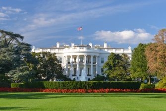 The White House building with a clear blue sky and well-maintained gardens in the foreground.