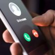 A hand holding a smartphone displaying an incoming call from an unknown number. A hand holding a smartphone displaying an incoming call from an unknown number.
