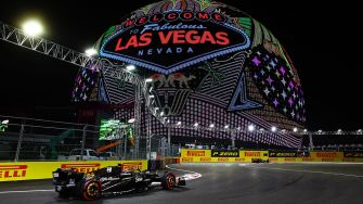 Formula 1 cars racing under the iconic "Welcome to Fabulous Las Vegas Nevada" sign at night during the Las Vegas Grand Prix.