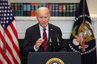 President Joe Biden speaking about student loan relief, with the U.S. flag and presidential seal in the background.