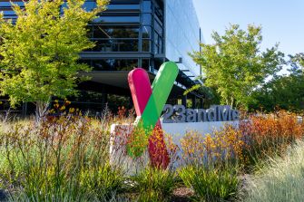 Sign at the entrance of the 23andMe headquarters, featuring the company's logo surrounded by greenery and flowers.