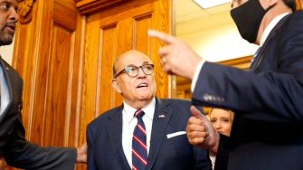 Rudy Giuliani appearing in a legal setting, surrounded by individuals during a discussion.