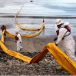 Workers in protective gear deploy oil spill containment booms along a beach affected by the 2015 Santa Barbara oil spill. Workers in protective gear deploy oil spill containment booms along a beach affected by the 2015 Santa Barbara oil spill.
