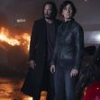 A scene from "The Matrix Resurrections" featuring two main characters standing in front of a burning vehicle. A scene from "The Matrix Resurrections" featuring two main characters standing in front of a burning vehicle.