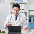 A doctor in a white coat engaging in a telemedicine consultation using a tablet in an office setting. A doctor in a white coat engaging in a telemedicine consultation using a tablet in an office setting.
