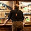 A person looking at a display of firearms in a shop. A person looking at a display of firearms in a shop.