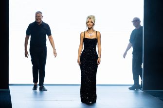 Kim Kardashian walking the runway in a black sequined gown during a fashion event.