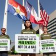 Three Greenpeace supporters holding signs that read "Energy Transfer: Democracy Runs on Free Speech, Not Oil & Gas" in front of flags and a building. Three Greenpeace supporters holding signs that read "Energy Transfer: Democracy Runs on Free Speech, Not Oil & Gas" in front of flags and a building.